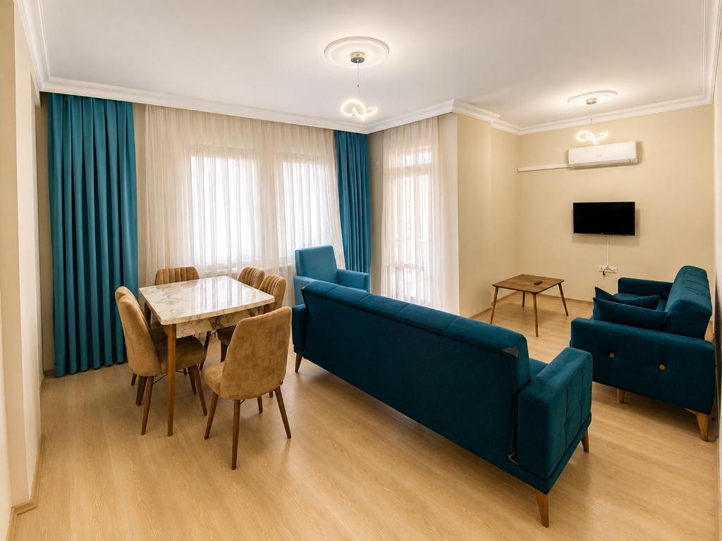 a living room with a couch and a table and chairs at Blue61 Residence Airport in Pelitli