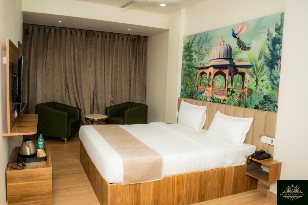 a hotel room with a bed and a painting on the wall at Sweekar Executive in Tuljapur