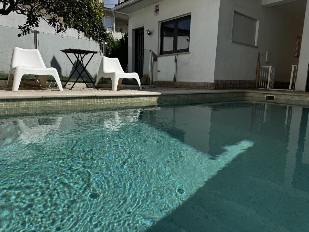 a swimming pool with two chairs and a table at Cascais House - Pool in Parede
