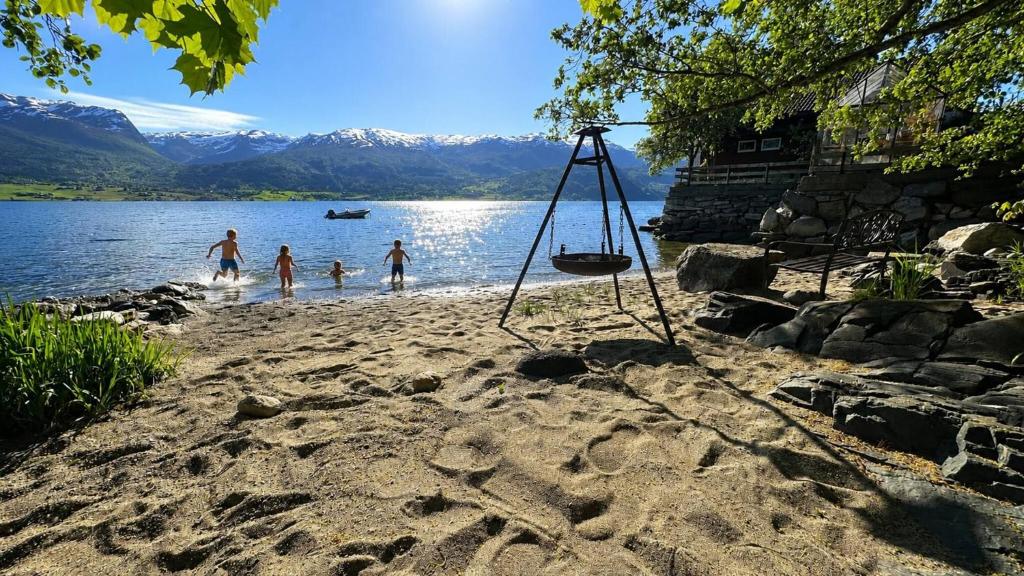 a group of people playing in the water on a beach at Charming Casa Hauge BB Sunset Room in Sandane