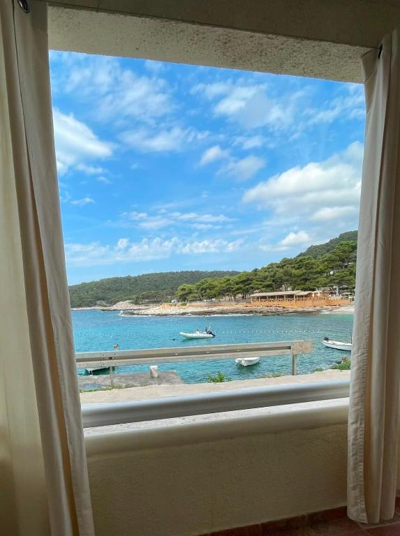 a window view of a beach with boats in the water at Studio apartment Milna, Hvar Buratovic in Hvar