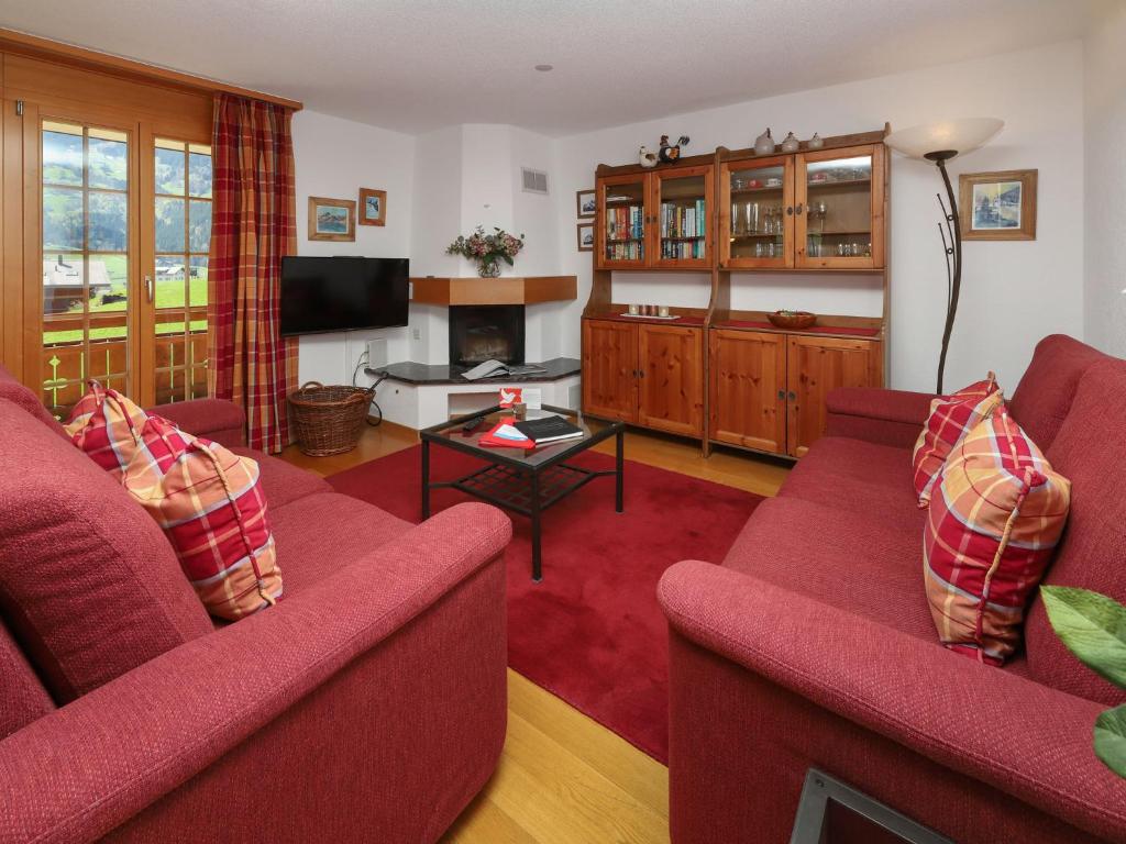 a living room with two red couches and a fireplace at Apartment Chalet Nagano by Interhome in Grindelwald