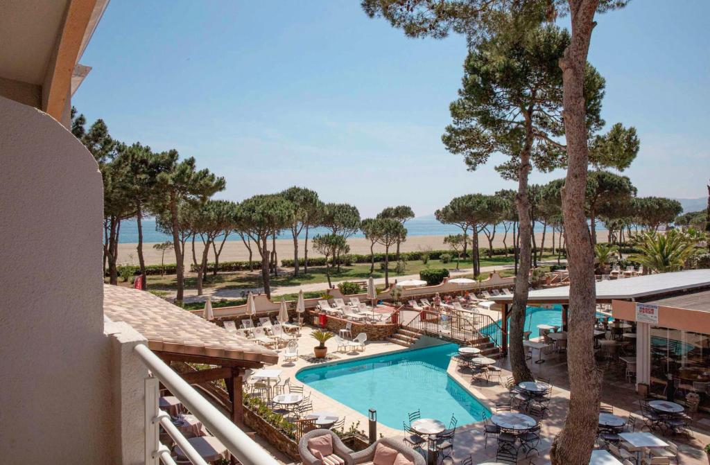 a view of the pool and beach from the balcony of a resort at Grand Hôtel Du Lido - sur la plage d'Argèles in Argelès-sur-Mer