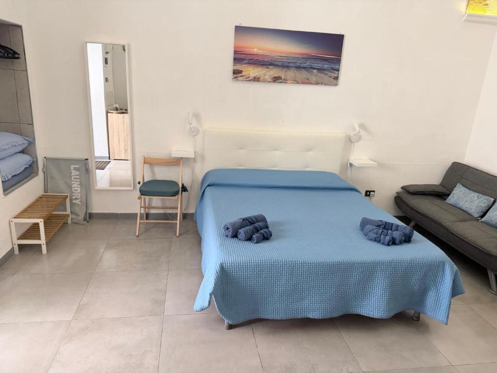 a bedroom with a blue bed and a couch at Monolocale Central Station in Brindisi