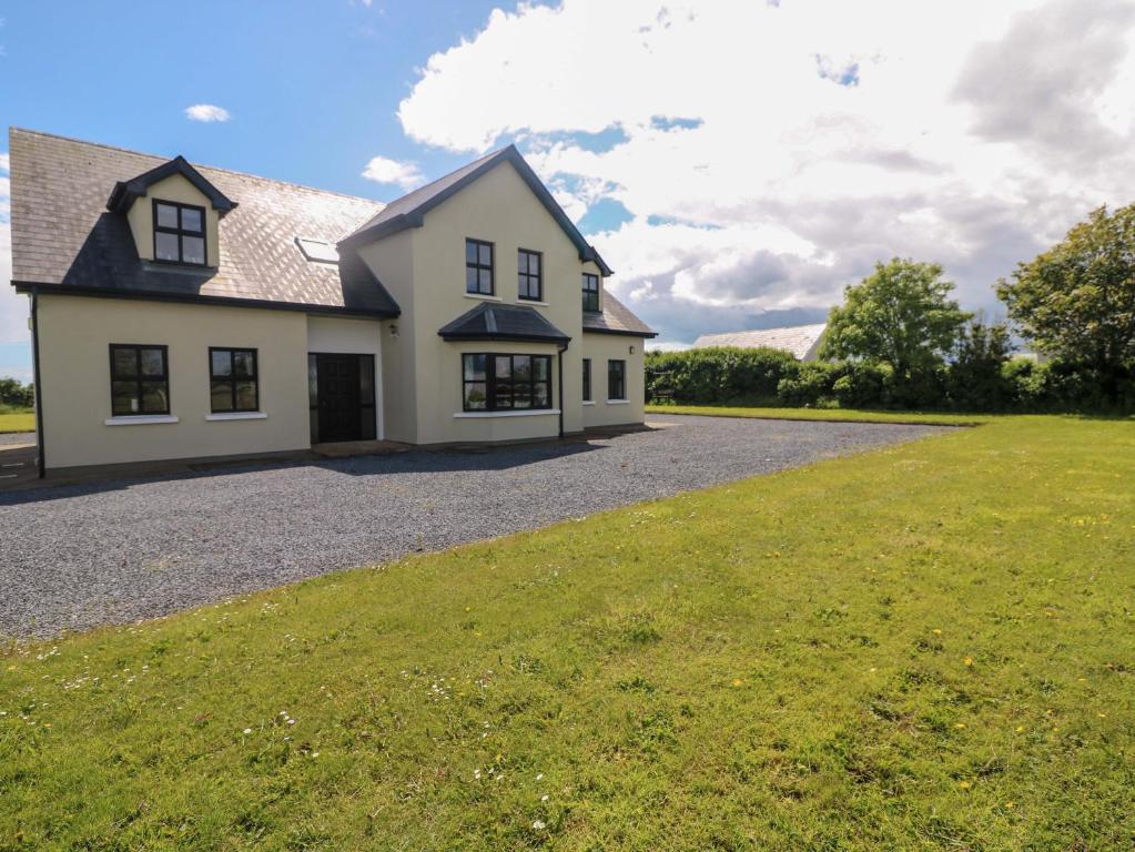 a white house with a large grass field at Strand House in Bannow