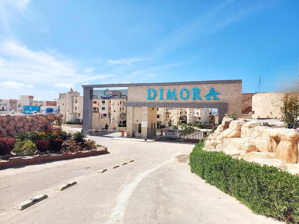 a building with a sign that reads dimora at شالية ديمورا للعائلات in Dawwār Muḩammad Abū Shunaynah
