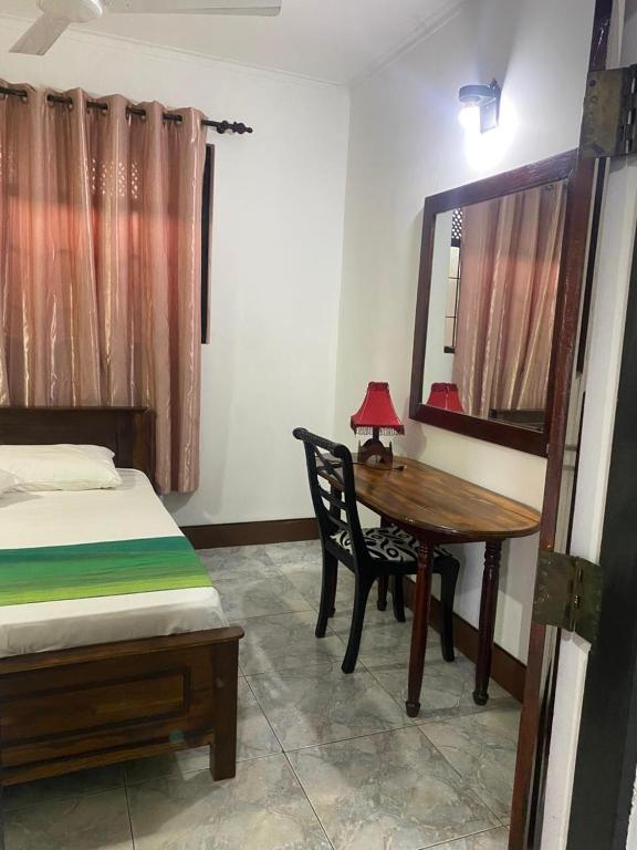 a bedroom with a bed and a table and a mirror at Courtyard Hostel Negombo in Negombo
