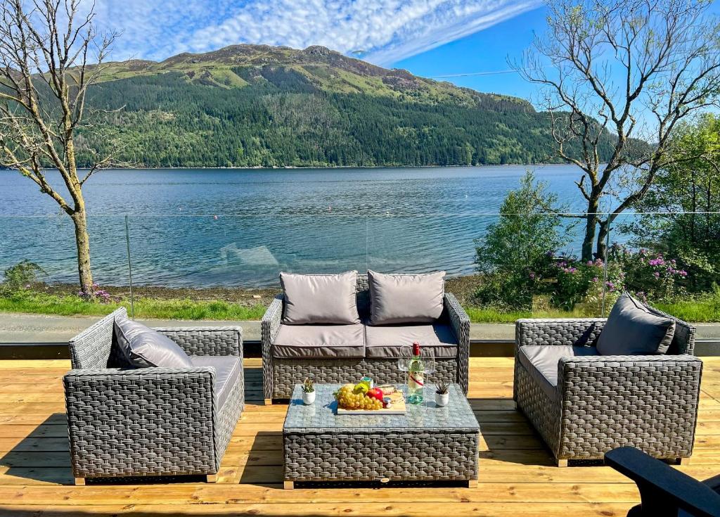 a patio with couches and a table and a lake at Kilbride Lodge in Carrick