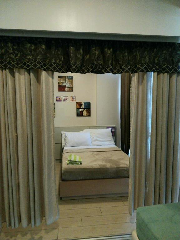 a bedroom with a bed with curtains and a window at Mactan Newtown Condo Rental in Punta Engaño