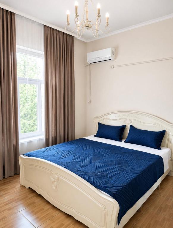 a bedroom with a bed with blue sheets and a chandelier at All residence in Almaty