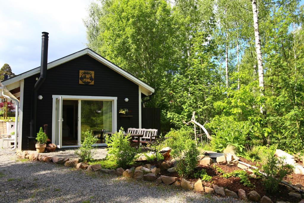 a black house with a bench in front of it at Schwedisches Waldcottage Fluss & Wanderwege in Fristad