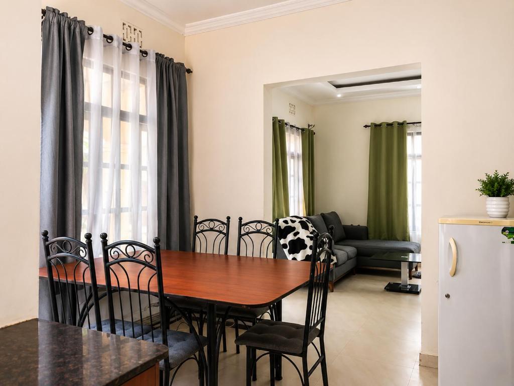 a dining table and chairs in a living room at Jules Place Arusha in Themi