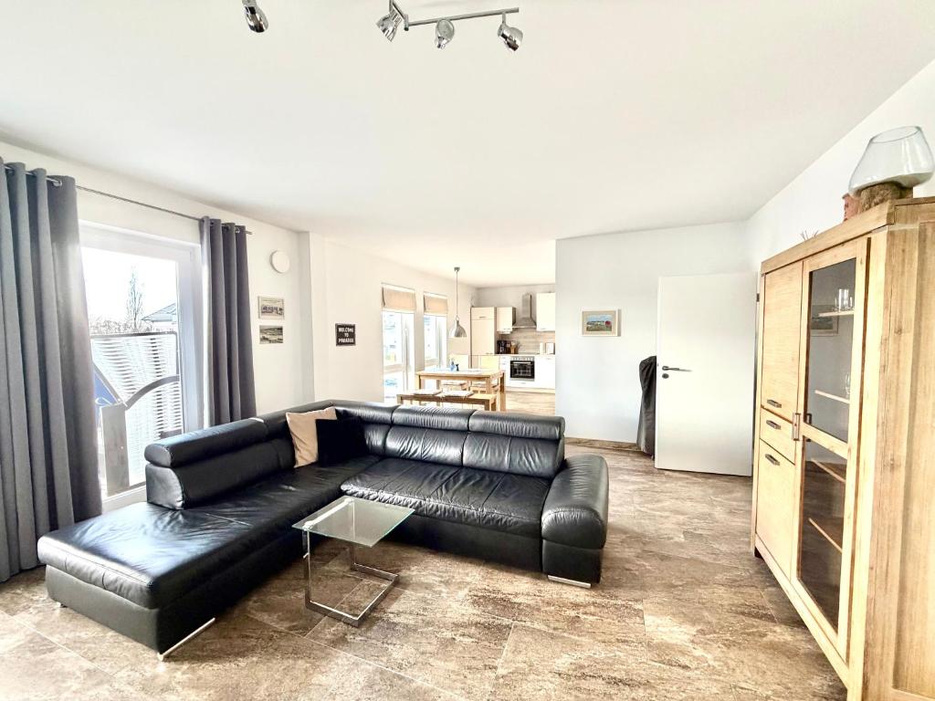 a living room with a black leather couch at Ferienwohnung Achterbrise mit Kamin in Zinnowitz