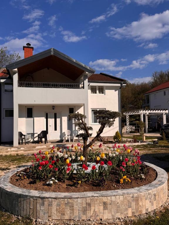 a house with a flower bed in front of a house at Sunny Valley Retreat near Skadar Lake in Virpazar