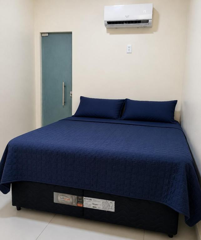 a bed with a blue comforter and a blue door at Suite Vila dos Cabanos Barcarena in Barcarena