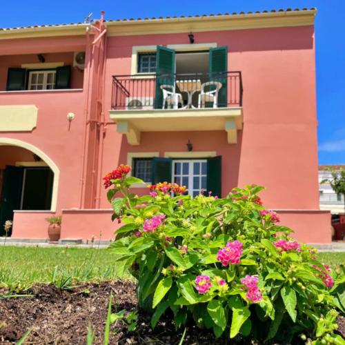 a pink building with a balcony and flowers in front of it at Exclusive Alexandra Apartments in Sidari