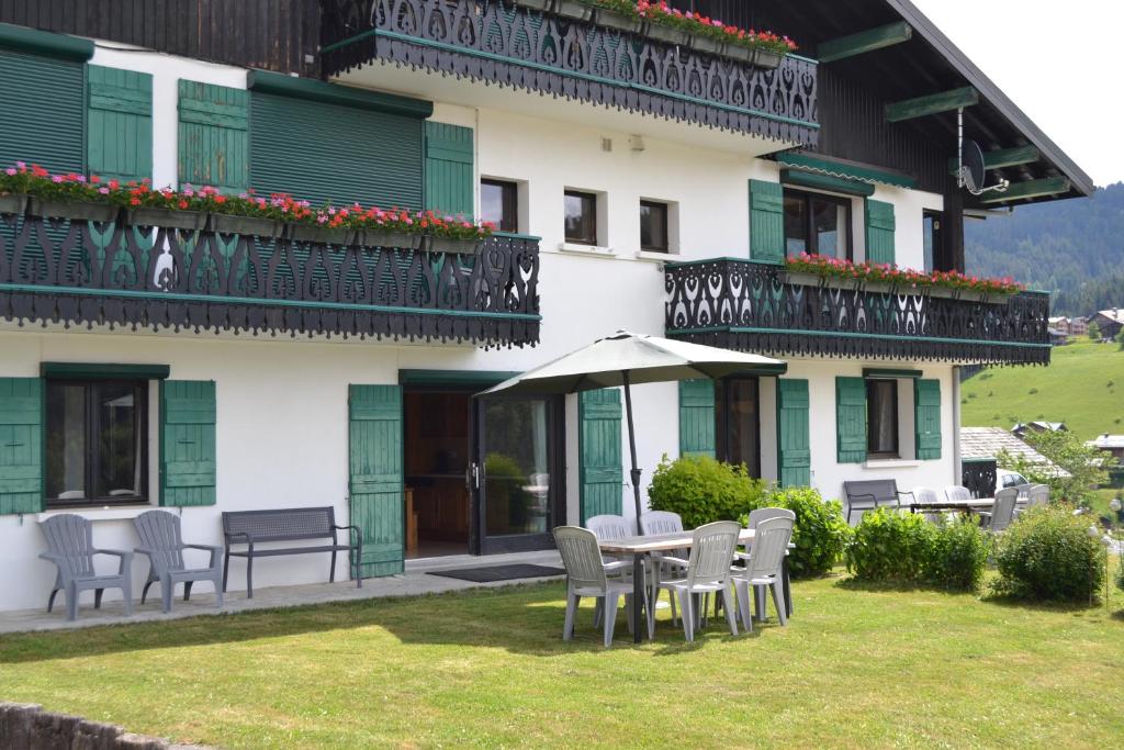 a building with a table and chairs and an umbrella at Chalet Fleur des Alpes 1 in Les Gets