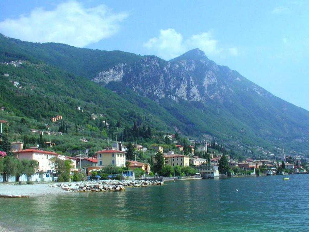 a town on the shore of a lake with a mountain at Hotel Lido in Gargnano