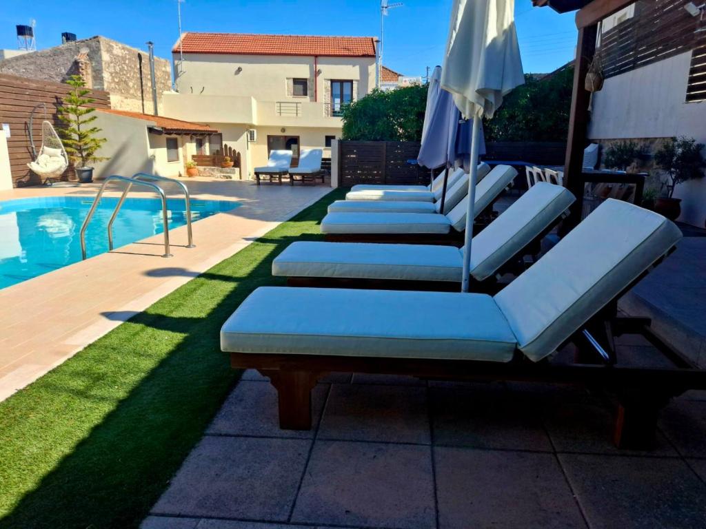 a row of lounge chairs with an umbrella next to a swimming pool at Villa Thalasena in episkopi-heraklion