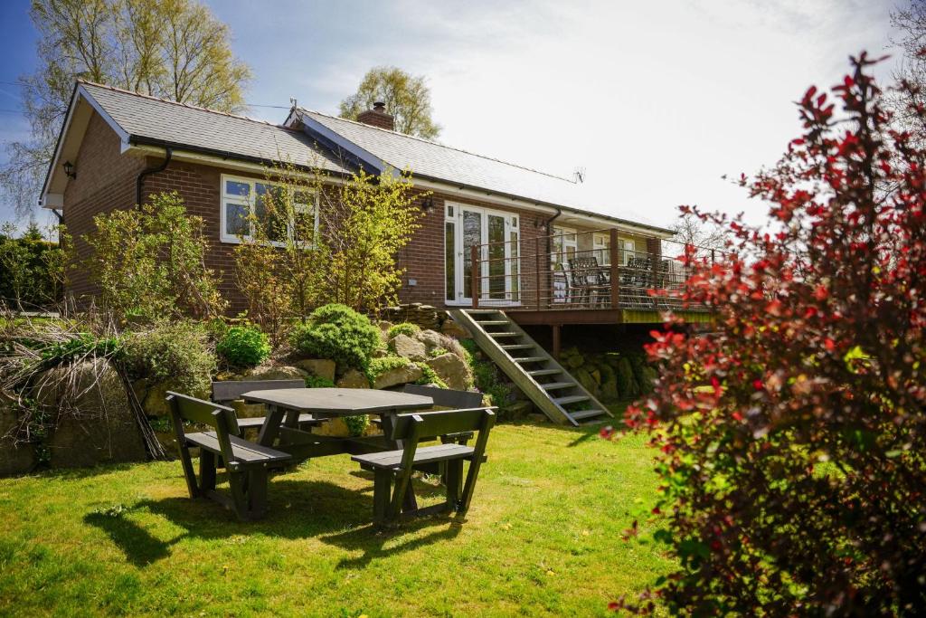 a house with a table and chairs in the yard at Ger Yr Afon in Saint Harmon