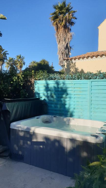 a hot tub in a yard with a fence and a palm tree at Maison MATIASMA avec Jacuzzi in Hyères