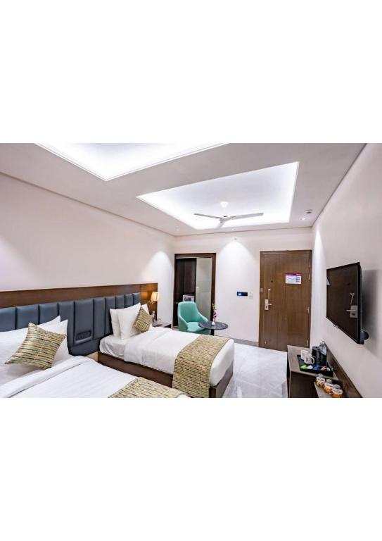 a hotel room with two beds and a flat screen tv at Hotel Raaj Palace in Agra
