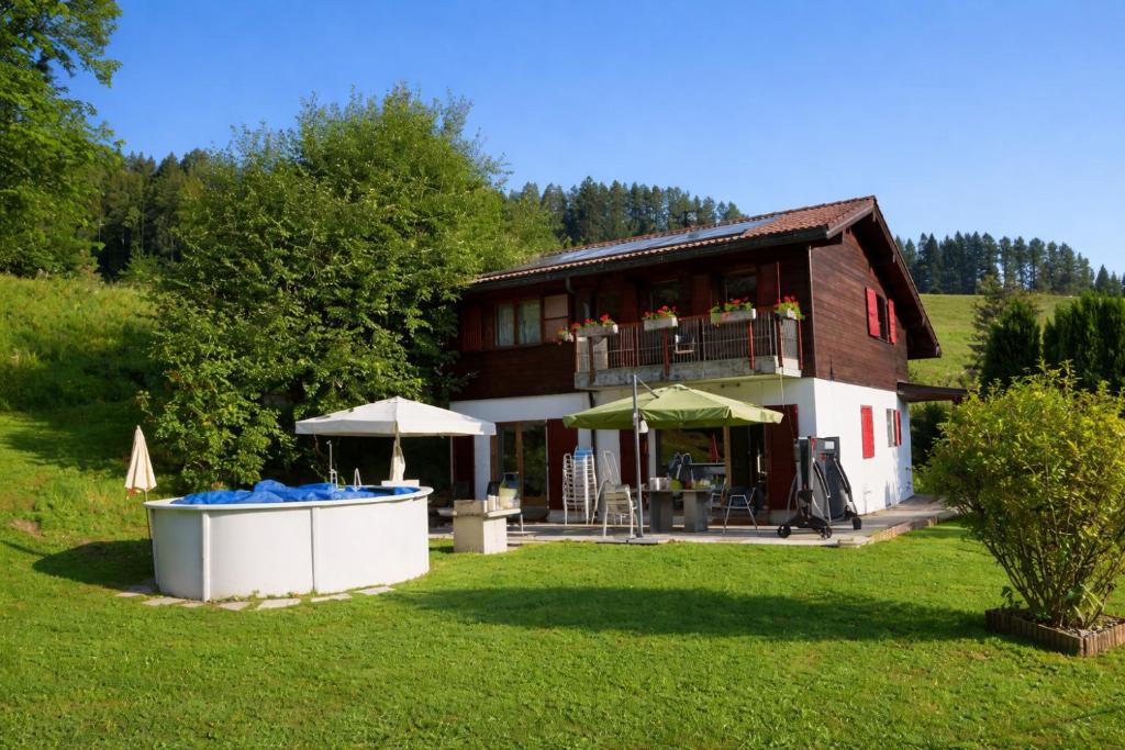 a large house with a balcony and a yard at Résidence les Papaillons in Enney