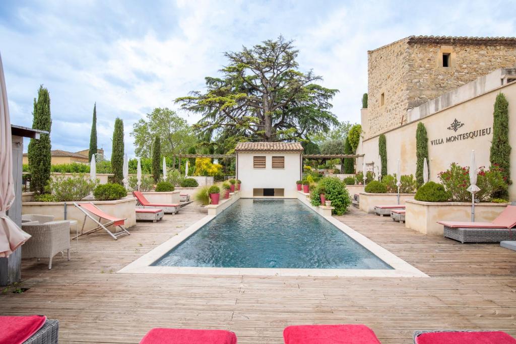 a pool in the middle of a patio with chairs and a building at Boutique Hôtel La Villa Montesquieu & sa piscine in Laudun