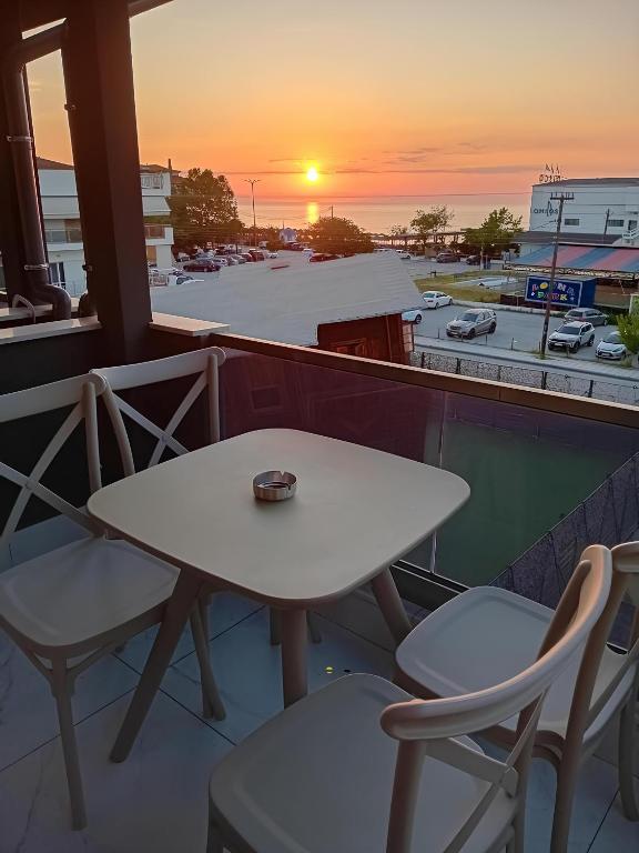 a table and chairs on a balcony with a sunset at IFI Apartments in Paralia Katerinis