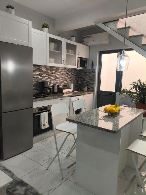 a kitchen with a counter with chairs and a refrigerator at Cantinho de Mindelo in Mindelo