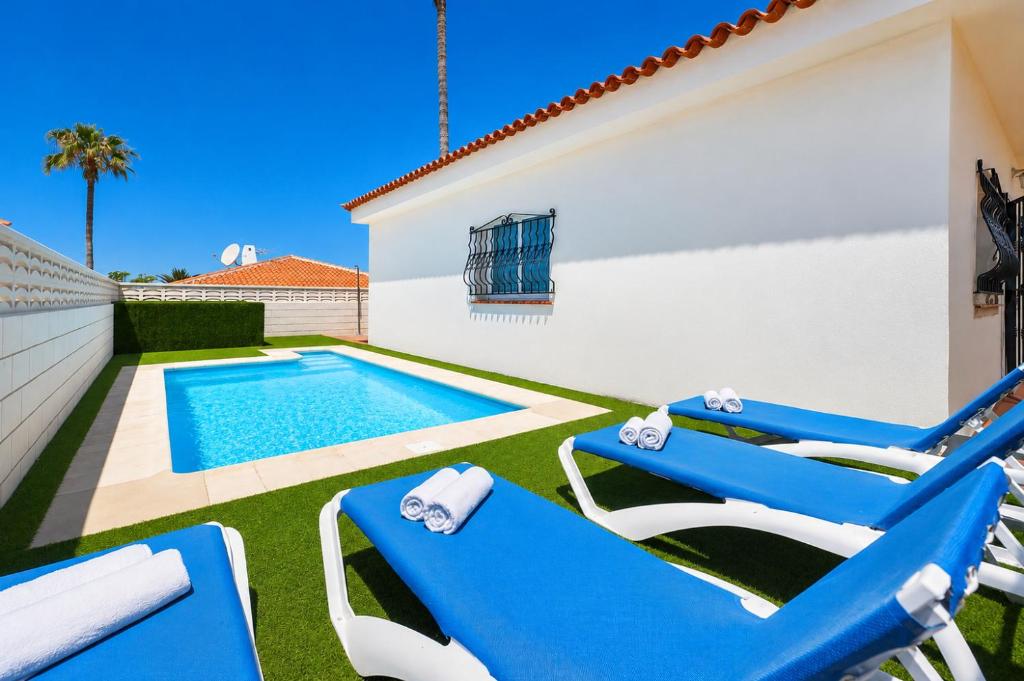 a patio with blue chairs and a swimming pool at CHALET 83 con PISCINA PRIVADA in Callao Salvaje
