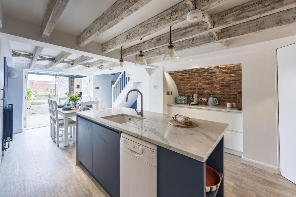 a kitchen with blue cabinets and a brick wall at Watch Cottage in Lymington