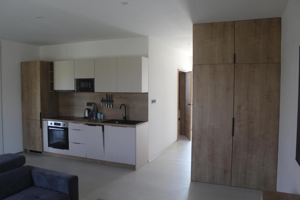 a kitchen with white cabinets and a couch in a room at Apartmány Nitrianska osada in Bánov