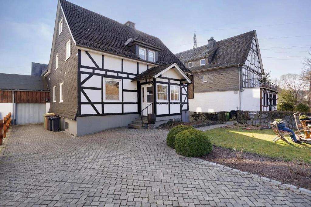 a large black and white house with a driveway at Apartment Huckelberg in Schmallenberg