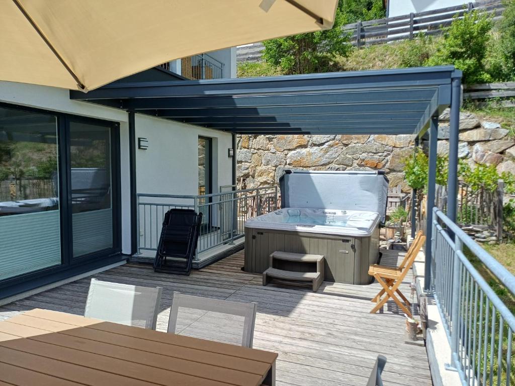 a patio with a hot tub and a grill on a deck at Ferienhaus Lurger in Strassen