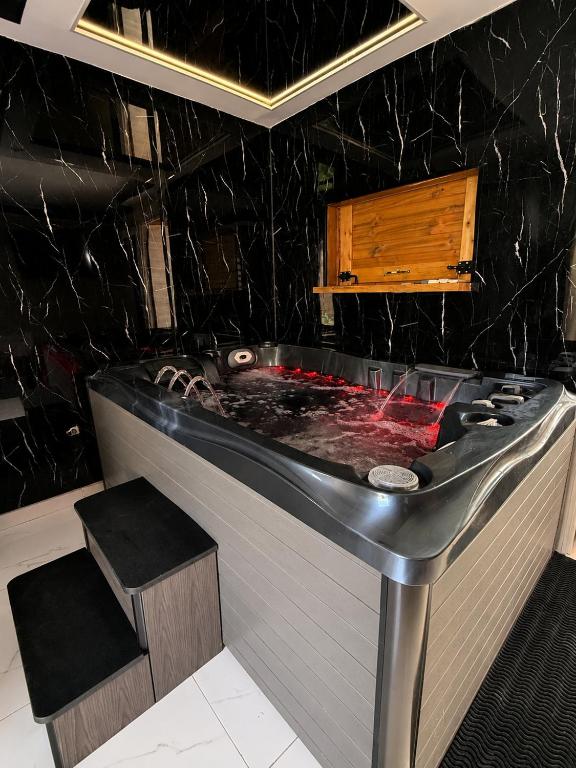a black bathroom with a bath tub with a stool at Love room Coconut Secret in Le Gosier