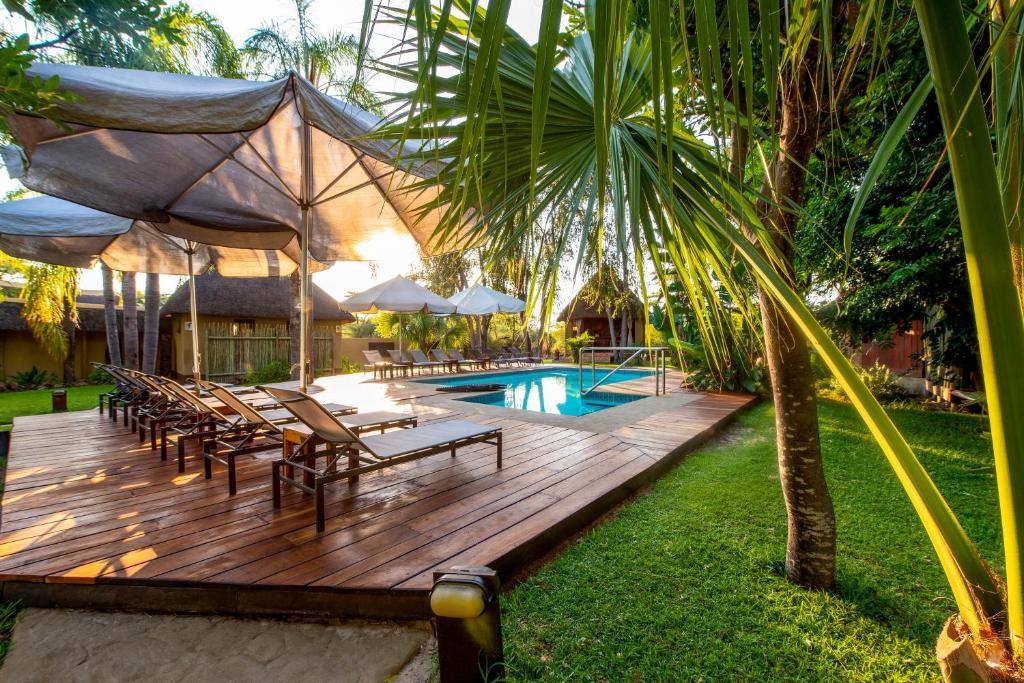 a wooden deck with chairs and a swimming pool at Gondwana Hakusembe River Lodge in Rundu