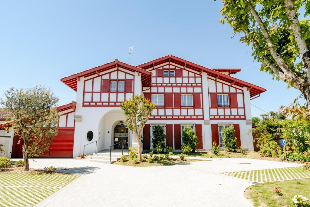 a red and white house with a red garage at Hôtel Villa Maïtia in Ustaritz