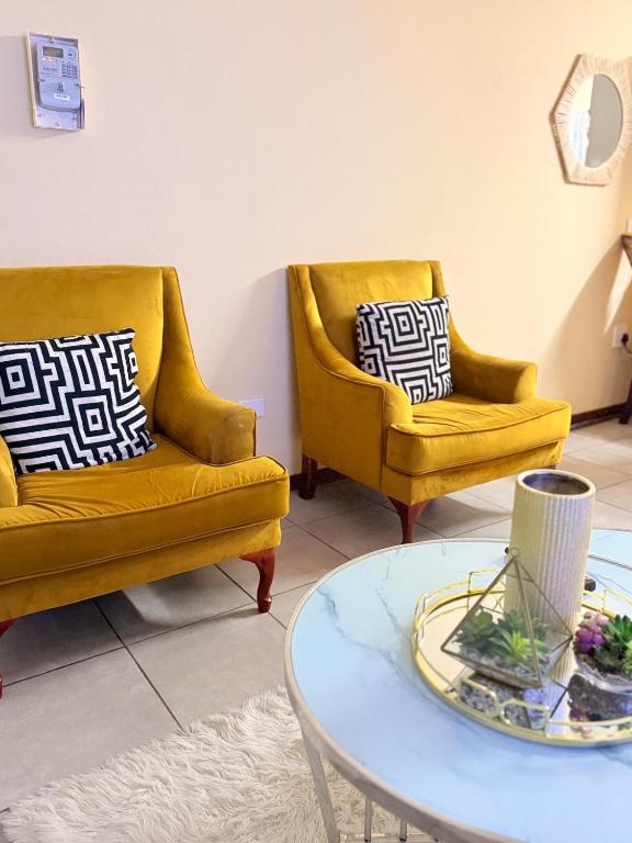 two yellow chairs and a table in a living room at Kilimanjaro in Alberton