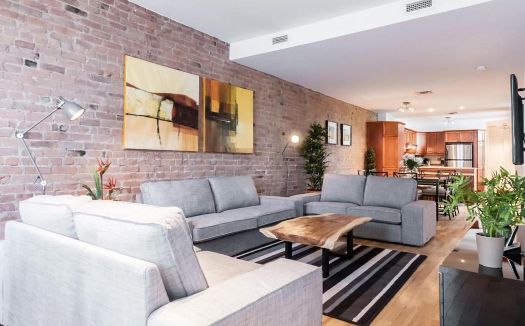 a living room with two couches and a brick wall at Le Metro Mont-Royal by HomeInMontreal in Montreal