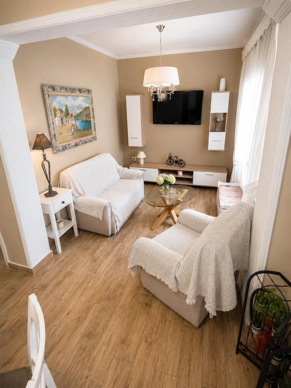 a living room with white furniture and a flat screen tv at ALICE'S ARt HOUSE in Kavála