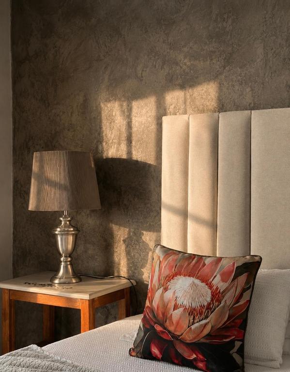 a bed with a pillow and a lamp on a table at Guesthouse 52 in Groblersdal
