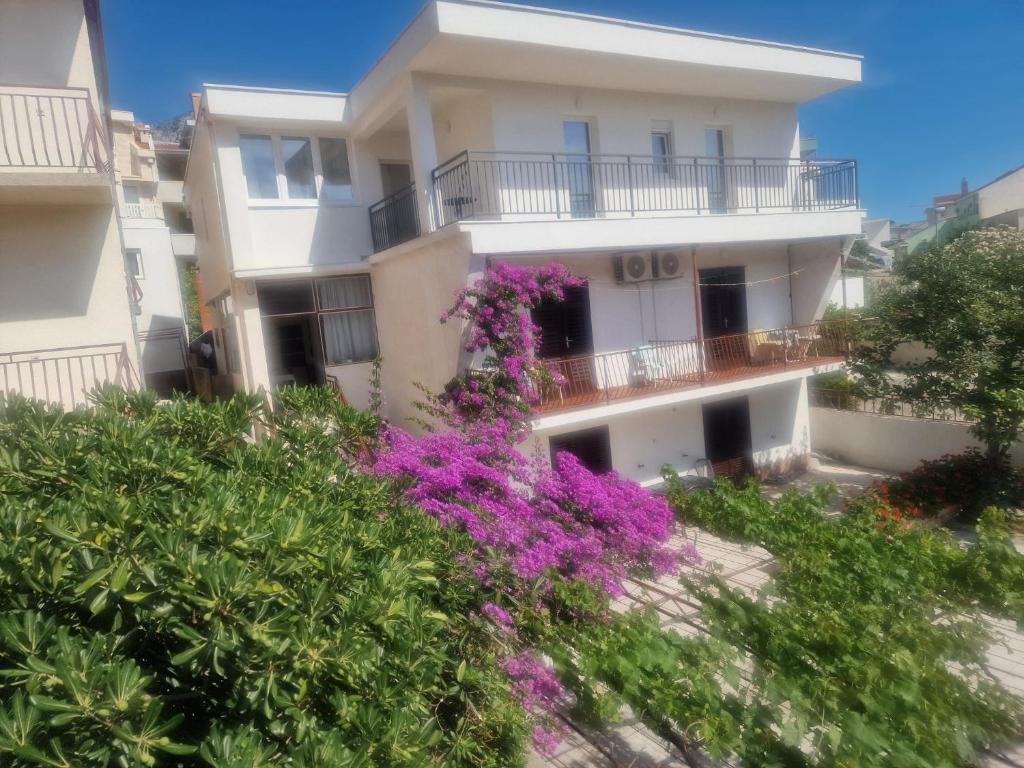a building with purple flowers in front of it at Apartmani Batinović - Baška Voda in Baška Voda