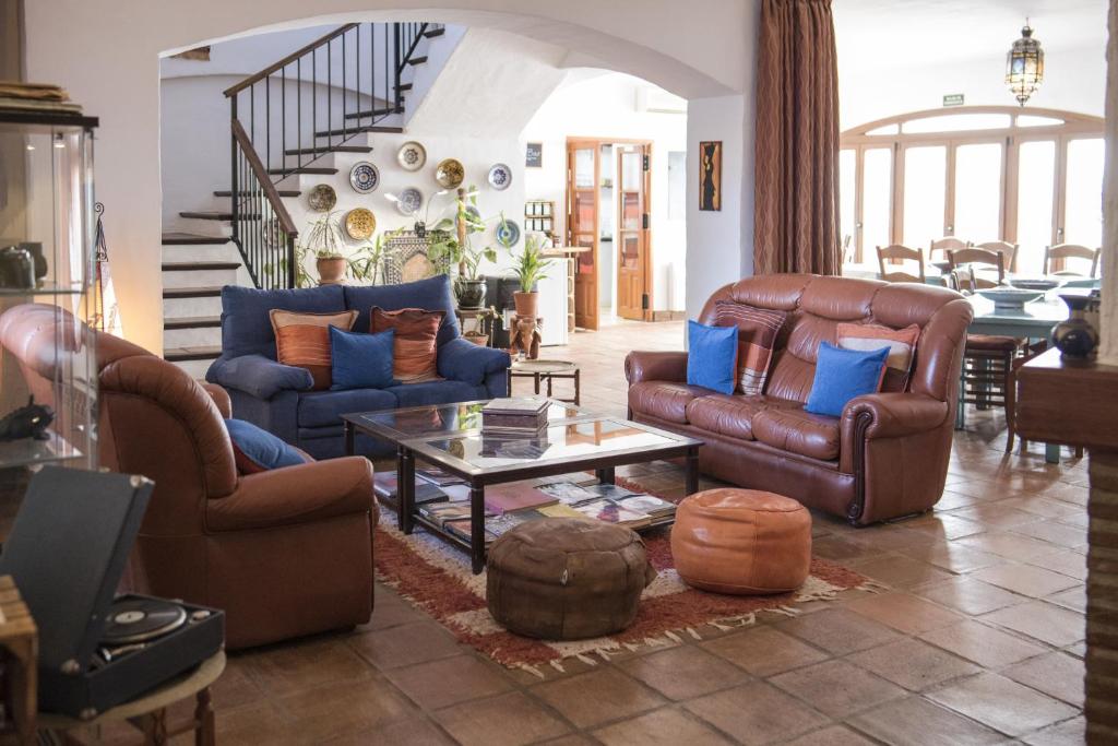a living room with leather furniture and a staircase at Hotel Los Castaños in Cartajima