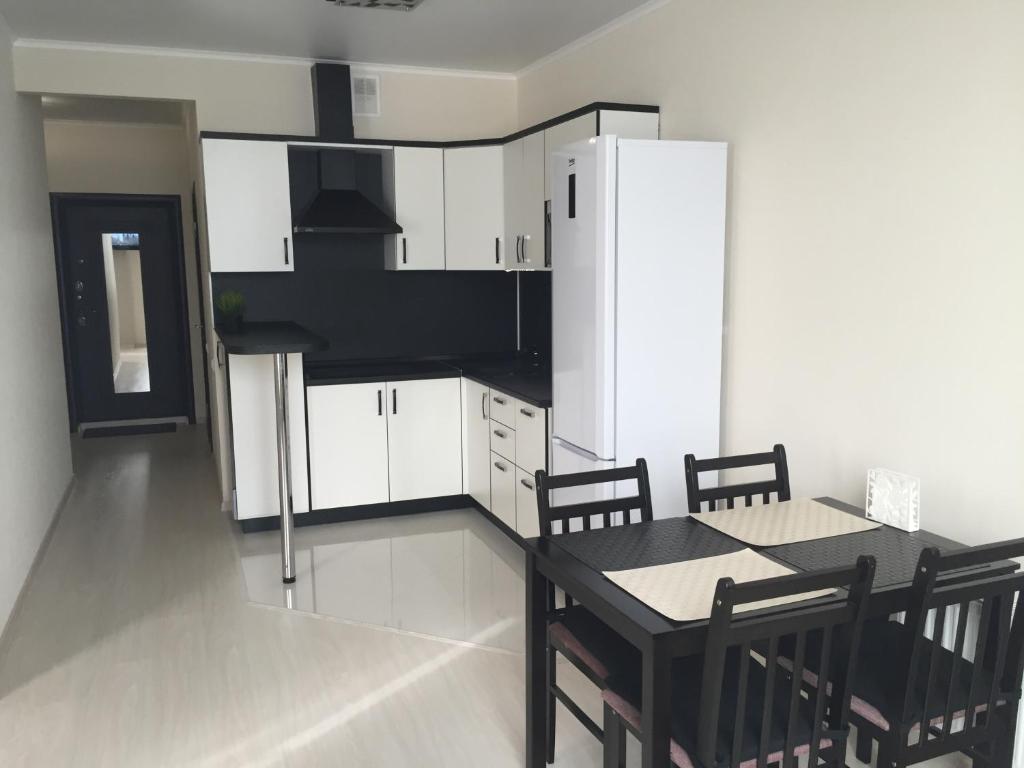 a kitchen with a table and a white refrigerator at Apartments on Konstantina Obraztsova in Krasnodar