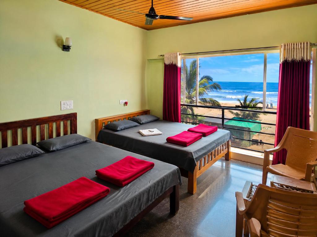two beds in a room with a view of the ocean at Gokarna Govekar Sea Facing Rooms in Gokarn