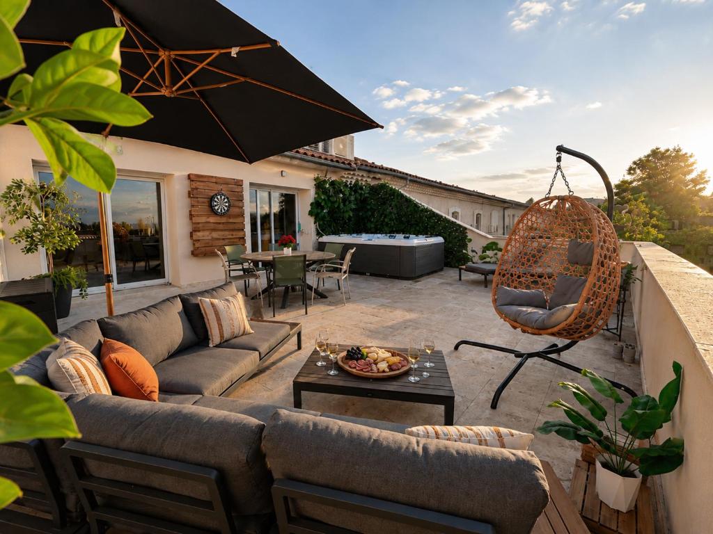 a patio with a couch and a table and an umbrella at Les Arches d'Or - Loft 200 m2 avec Rooftop, Jacuzzi et 3 Suites - Centre 5 min - Proche A7-A9 in Orange