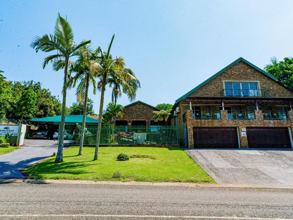 a house with two palm trees in front of it at Emoyeni Guest House in Nelspruit