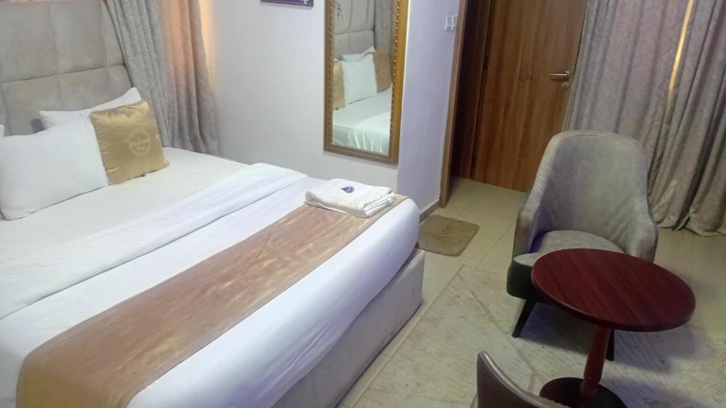 a hotel room with a bed and a chair and a mirror at D'Mayor Suites, Gwarinpa in Gwarinpa