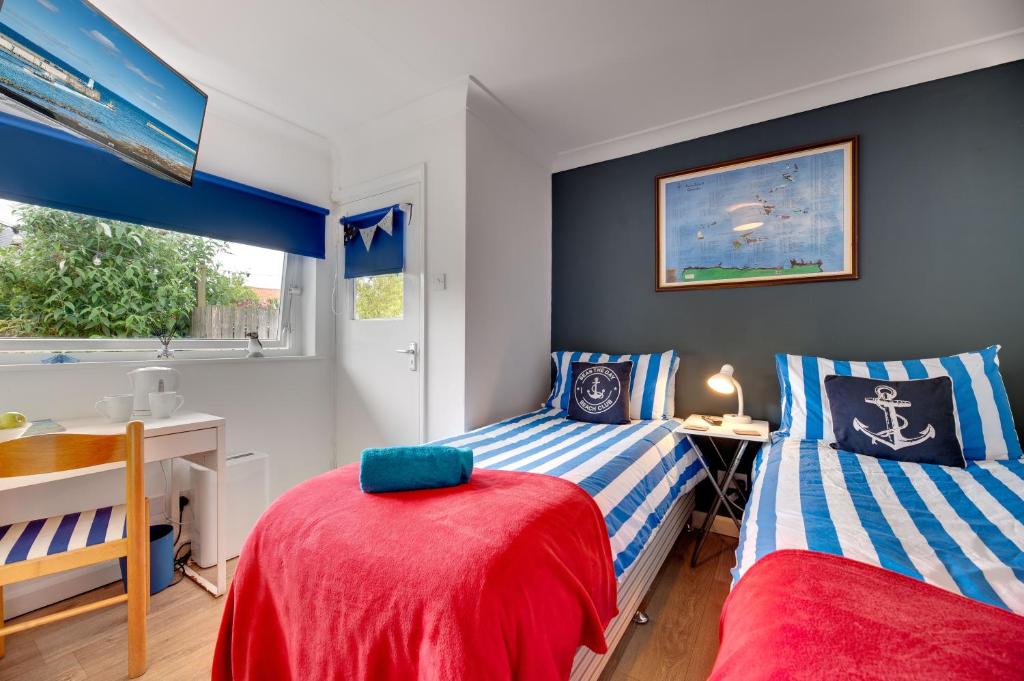 a bedroom with two beds and a desk and a window at The Hides in Seahouses